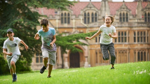 Three children run across the grass at Tyntesfield, Somerset, with the house in the background